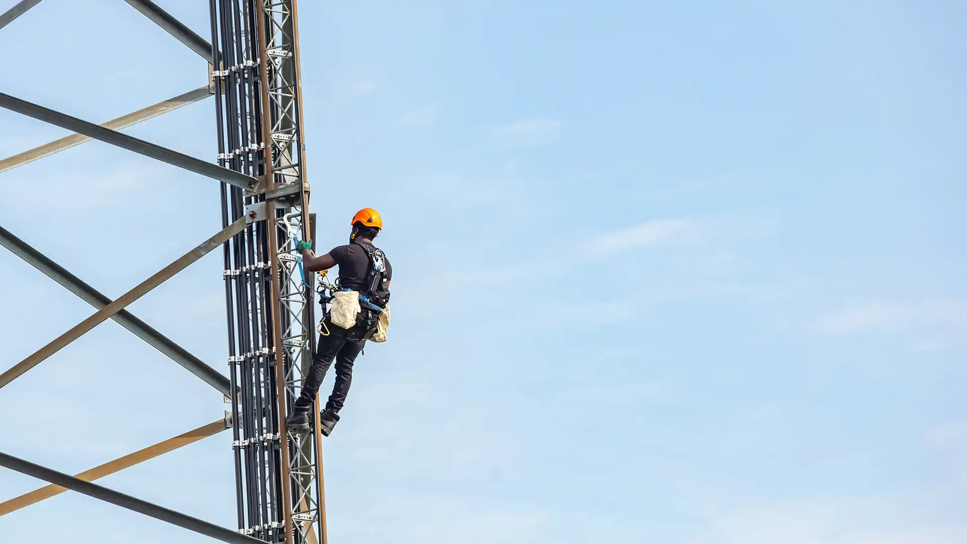A worker using a Retractable Fall Arrest and a safety harness is working safely on the tower.