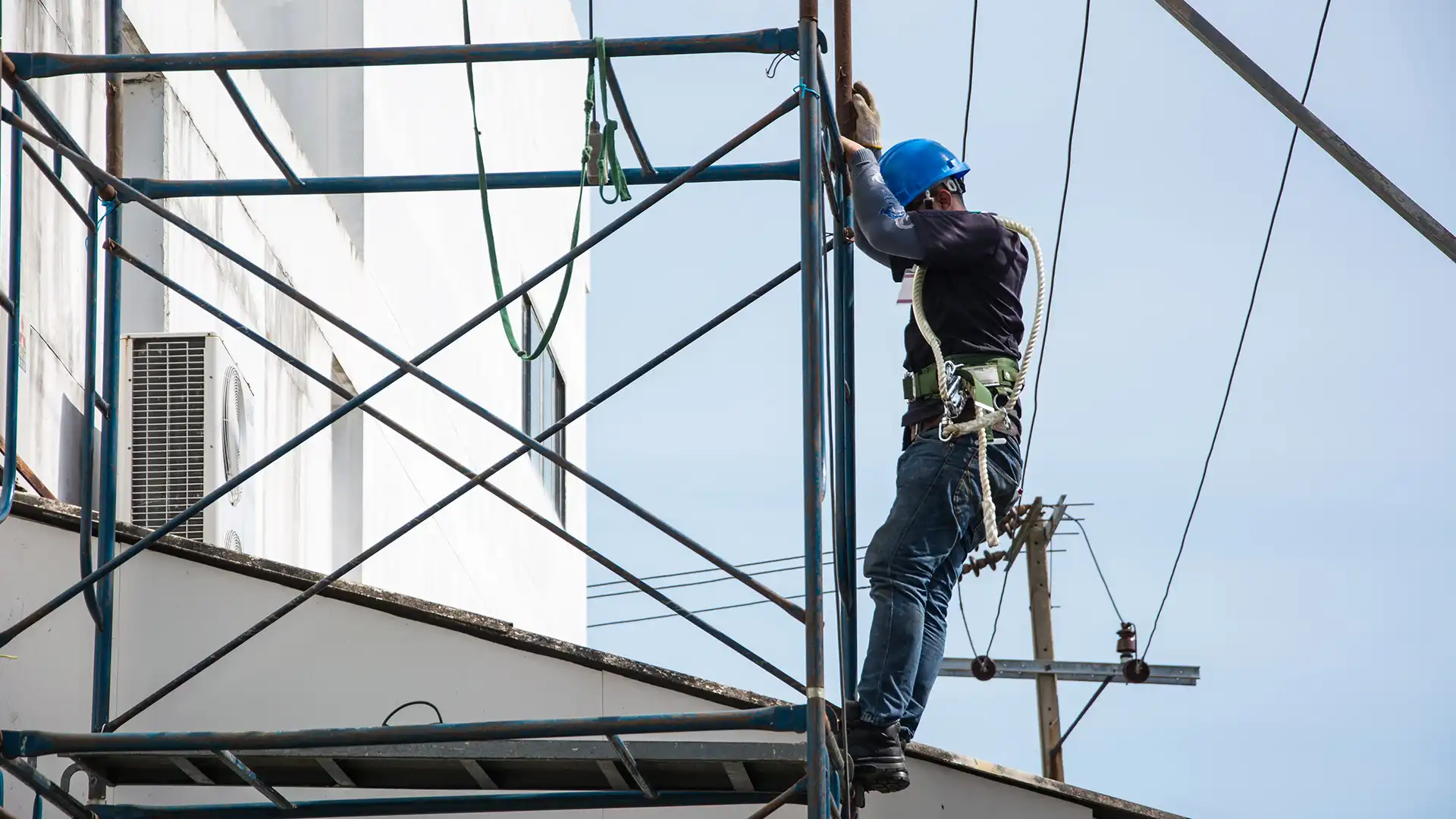 A worker on scaffolding is working safely at height using a Retractable Fall Arrest and a lanyard.