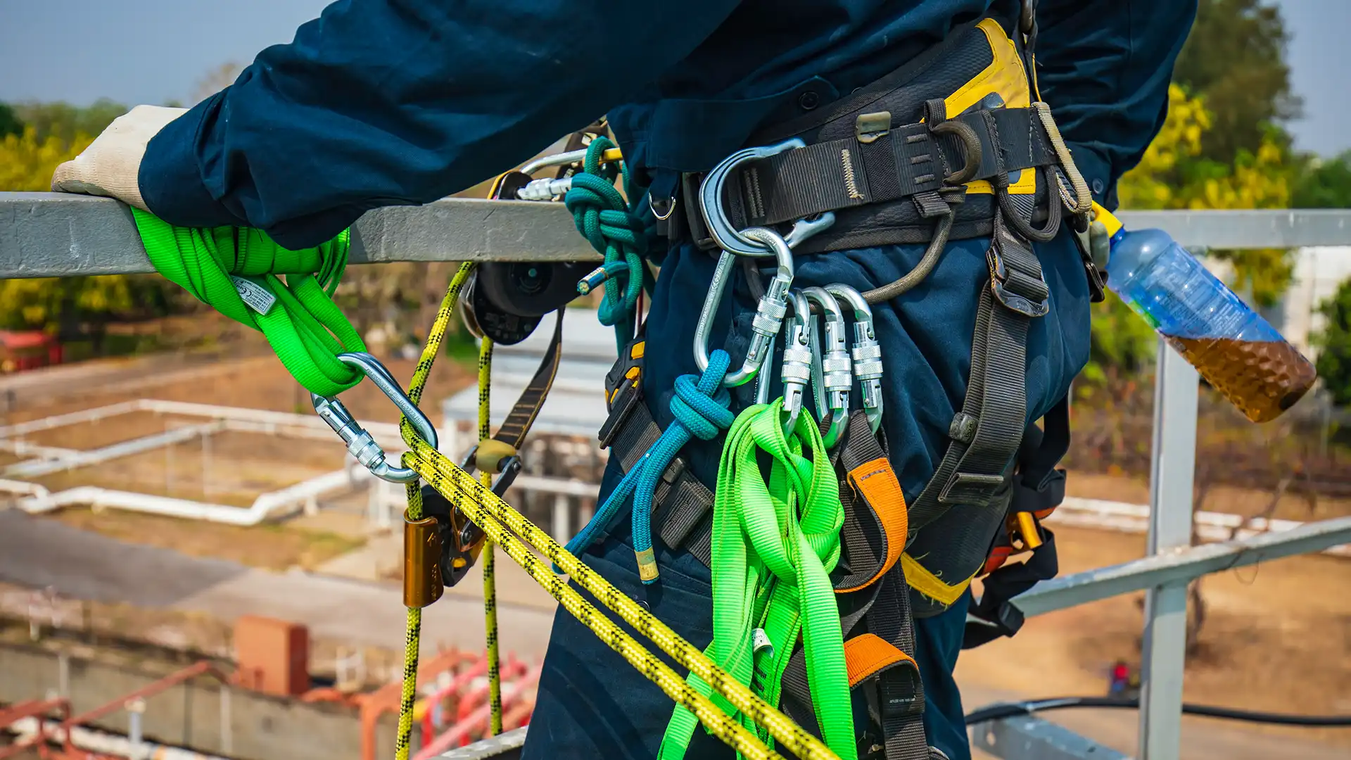 Yüksekte çalışan işçi, emniyet kemeri, karabinalar ve lanyard sistemiyle güvenli şekilde ankraj noktasına bağlı olarak çalışıyor.