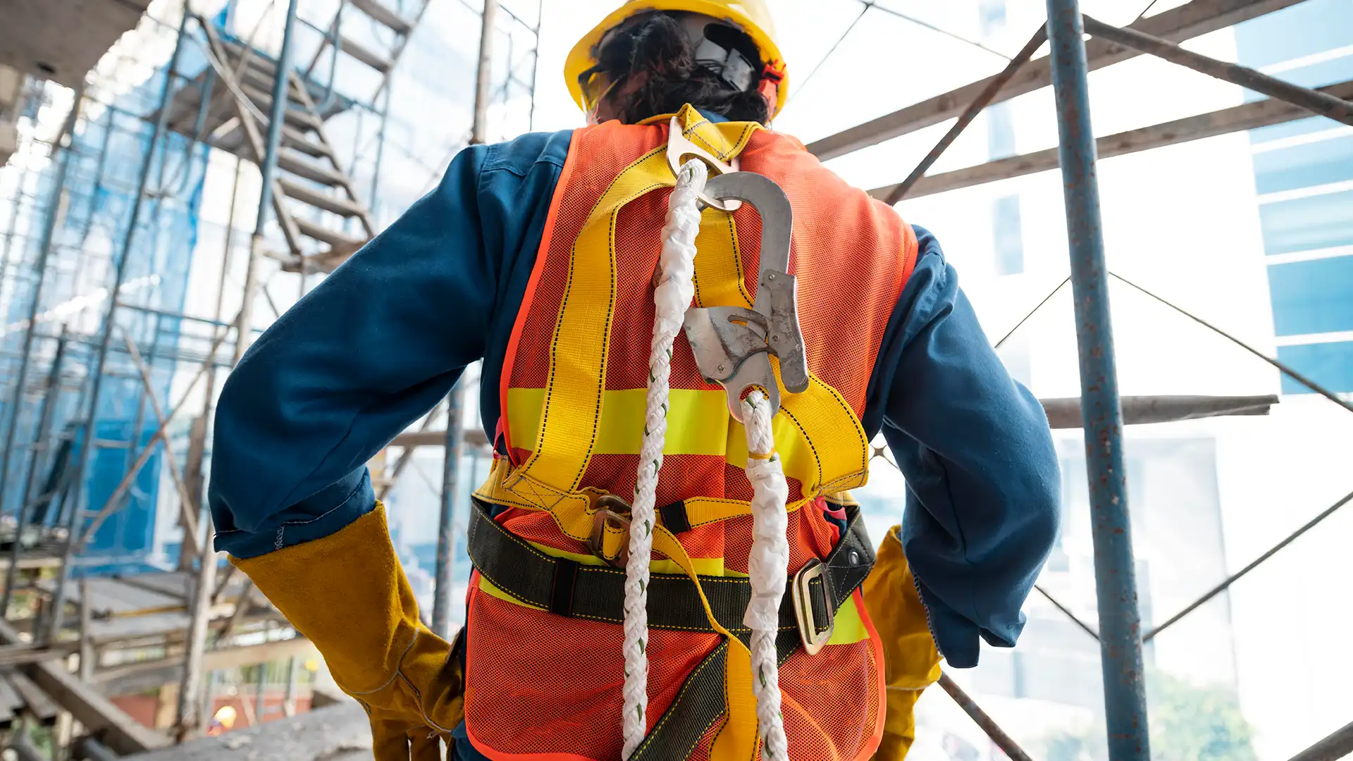 A worker using a full body harness and an energy absorbing lanyard at a construction site.